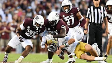 Aug 31, 2024; College Station, Texas, USA;  Texas A&M Aggies linebacker Taurean York (21) and defensive lineman Albert Regis (17) tackle Notre Dame Fighting Irish quarterback Riley Leonard (13) during the second quarter at Kyle Field. Mandatory Credit: Maria Lysaker-Imagn Images