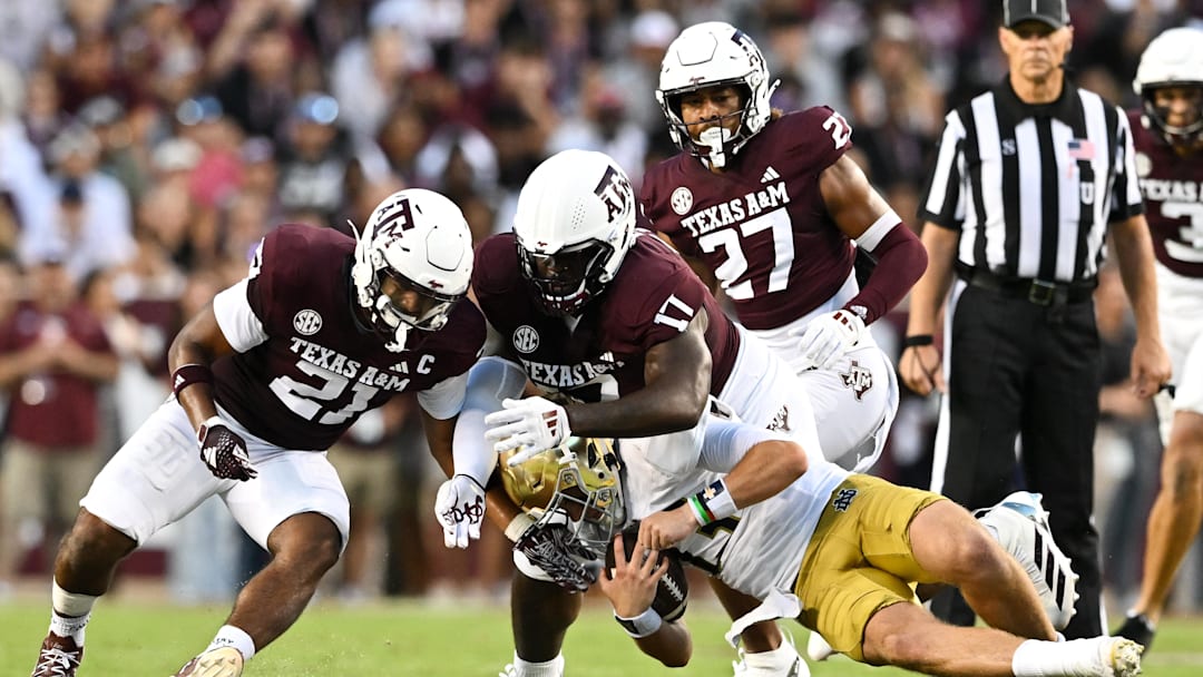 Aug 31, 2024; College Station, Texas, USA;  Texas A&M Aggies linebacker Taurean York (21) and defensive lineman Albert Regis (17) tackle Notre Dame Fighting Irish quarterback Riley Leonard (13) during the second quarter at Kyle Field. Mandatory Credit: Maria Lysaker-Imagn Images
