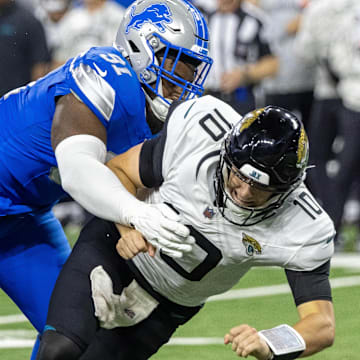 Nov 17, 2024; Detroit, Michigan, USA; Jacksonville Jaguars quarterback Mac Jones (10) passes the ball and is pressured by Detroit Lions defensive end Levi Onwuzurike (91) during the second half at Ford Field. Mandatory Credit: David Reginek-Imagn Images