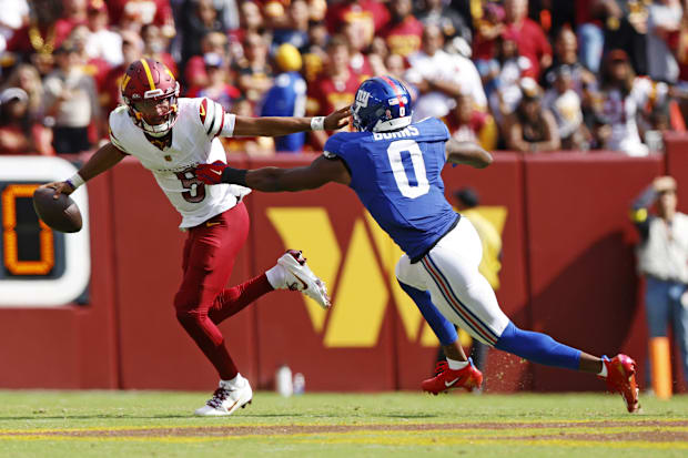 Washington Commanders quarterback Jayden Daniels runs from New York Giants linebacker Brian Burns. 