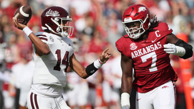 Mississippi State quarterback Mike Wright throws under pressure from Arkansas Razorbacks defensive end Trajan Jeffcoat 