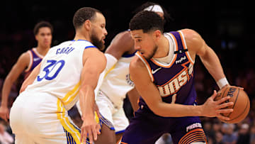Apr 8, 2025; Phoenix, Arizona, USA; Phoenix Suns guard Devin Booker (1) attempts to drive to the basket against Golden State Warriors guard Stephen Curry (30) during the second half at Footprint Center. Mandatory Credit: Mark J. Rebilas-Imagn Images