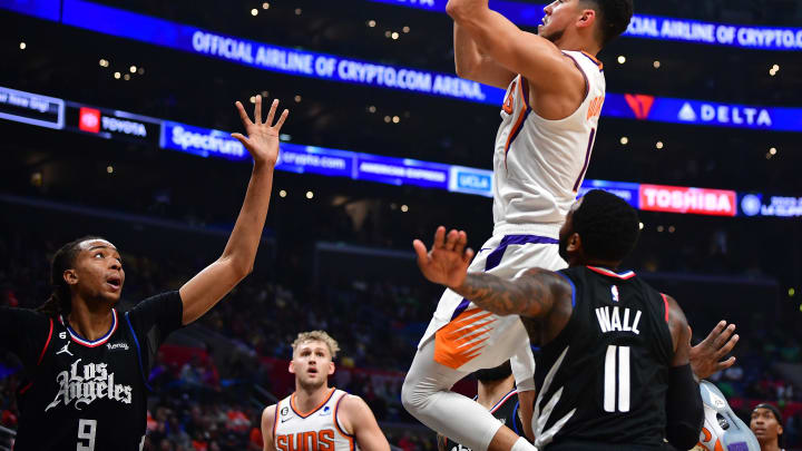 Dec 15, 2022; Los Angeles, California, USA; Phoenix Suns guard Devin Booker (1) shoots against Los Angeles Clippers center Moses Brown (9) and guard John Wall (11) during the second half at Crypto.com Arena. Mandatory Credit: Gary A. Vasquez-USA TODAY Sports