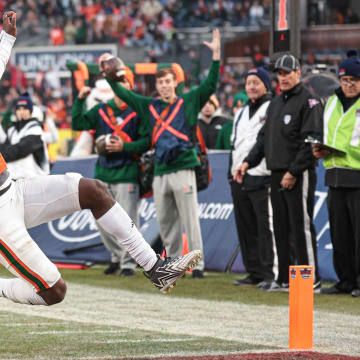 Dec 28, 2023; Bronx, NY, USA; Miami Hurricanes quarterback Jacurri Brown (11) scores a touchdown in front of defensive back Flip Dixon (10) during the first half of the 2023 Pinstripe Bowl at Yankee Stadium. Mandatory Credit: Vincent Carchietta-USA TODAY Sports