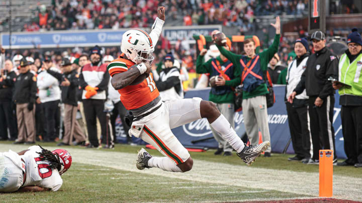 Dec 28, 2023; Bronx, NY, USA; Miami Hurricanes quarterback Jacurri Brown (11) scores a touchdown in front of defensive back Flip Dixon (10) during the first half of the 2023 Pinstripe Bowl at Yankee Stadium. Mandatory Credit: Vincent Carchietta-USA TODAY Sports