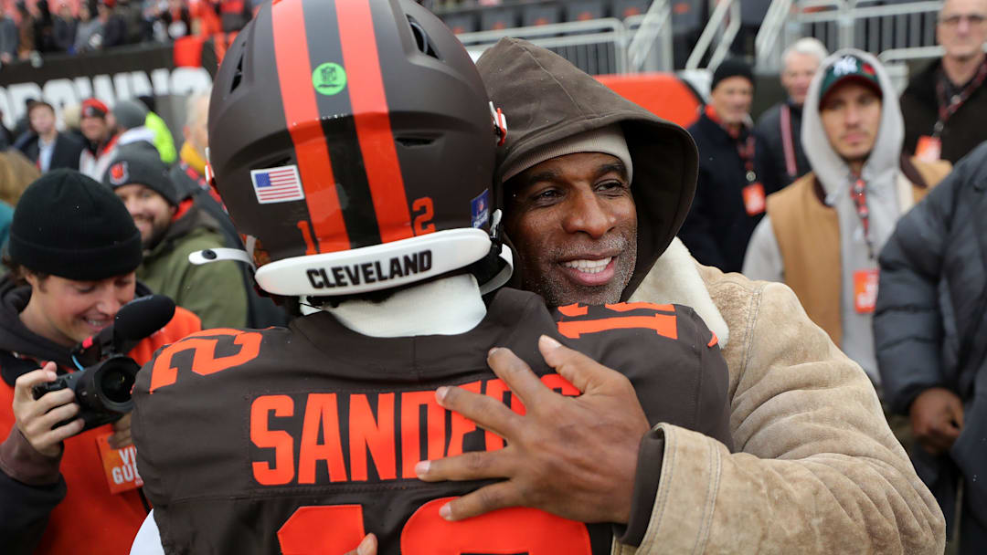 NFL legend Deion Sanders Sr., facing, hugs his son Shedeur Sanders before an NFL football game at Huntington Bank Field, Dec. 7, 2025, in Cleveland, Ohio.