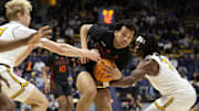 Jan 25, 2025; Berkeley, California, USA; Miami Hurricanes guard Divine Ugochukwu (middle) drives against California Golden Bears forward Rytis Petraitis (31) and guard DeJuan (DJ) Campbell (3) during the second half at Haas Pavilion. Mandatory Credit: D. Ross Cameron-Imagn Images