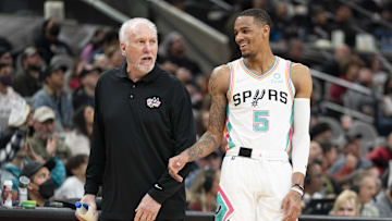 San Antonio Spurs head coach Gregg Popovich shares a laugh with guard Dejounte Murray.