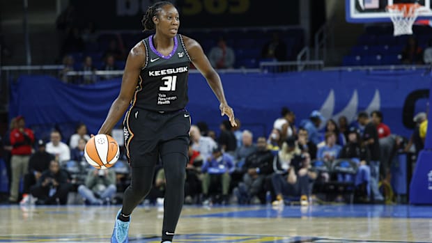 Connecticut Sun center Tina Charles dribbles the ball up the court, wearing a black jersey with a purple neckline. 