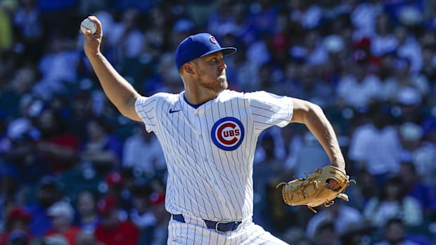Chicago Cubs starting pitcher Jameson Taillon throws in a white uniform and blue hat