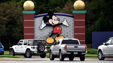 Cars drive past a sign featuring Mickey Mouse at the...