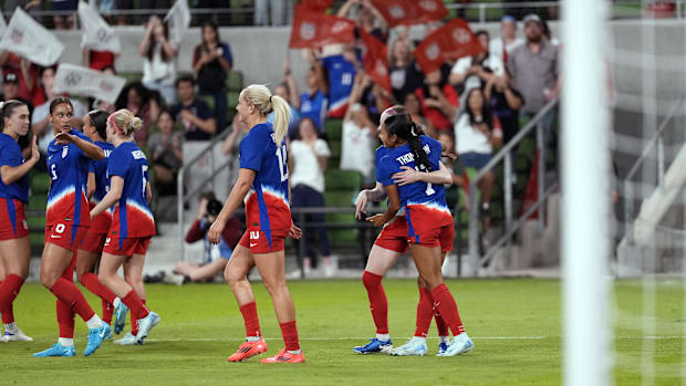 USA soccer players gather around and hug each other after scoring a goal against Iceland.