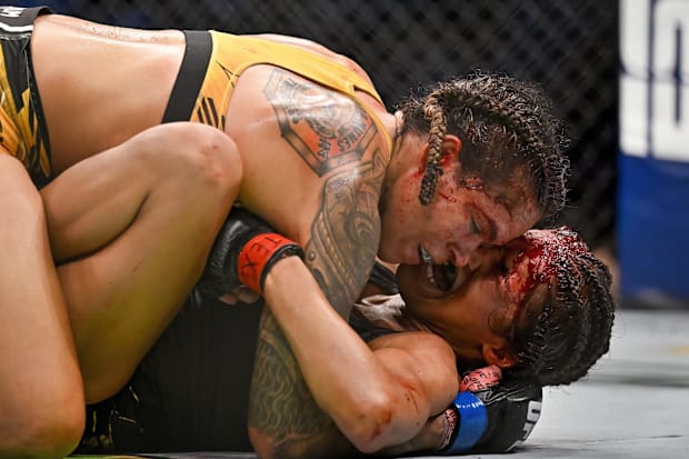 Julianna Pena (red gloves) fights Amanda Nunes (blue gloves) in a women's bantamweight title bout during UFC 277 at the Ameri