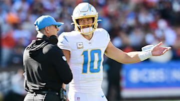 Nov 3, 2024; Cleveland, Ohio, USA; Los Angeles Chargers quarterback Justin Herbert (10) talks to head coach Jim Harbaugh during the first quarter against the Cleveland Browns at Huntington Bank Field. Mandatory Credit: Ken Blaze-Imagn Images