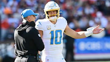 Nov 3, 2024; Cleveland, Ohio, USA; Los Angeles Chargers quarterback Justin Herbert (10) talks to head coach Jim Harbaugh during the first quarter against the Cleveland Browns at Huntington Bank Field. Mandatory Credit: Ken Blaze-Imagn Images
