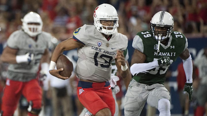 Sep 17, 2016; Tucson, AZ, USA; Arizona Wildcats quarterback Brandon Dawkins (13) runs the ball under pressure from Hawaii Warriors defensive back Trayvon Henderson (39) during the second quarter at Arizona Stadium. Mandatory Credit: Casey Sapio-Imagn Images