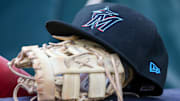Apr 24, 2024; Atlanta, Georgia, USA; A detailed view of a Miami Marlins hat and glove in the dugout before a game against the Atlanta Braves at Truist Park. 