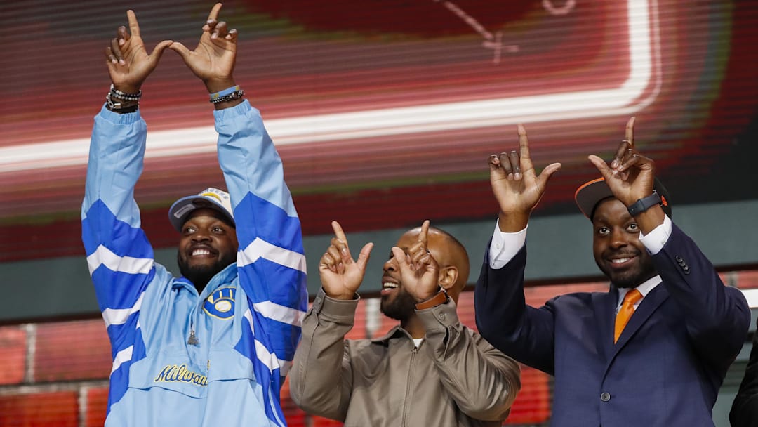 Apr 25, 2025; Green Bay, WI, USA; Former Wisconsin running backs Melvin Gordon, left, James White, center, and Montee Ball, right, make “W” gestures for the crowd before the second round of the 2025 NFL Draft at Lambeau Field. Mandatory Credit: Tork Mason/USA Today Network via Imagn Images