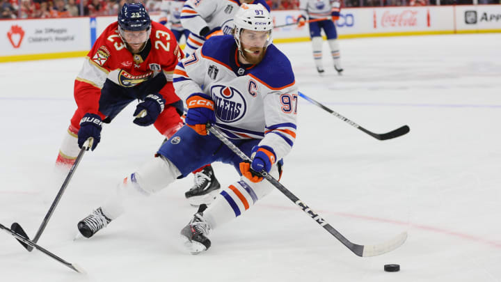 Jun 24, 2024; Sunrise, Florida, USA; Edmonton Oilers forward Connor McDavid (97) controls the puck as Florida Panthers forward Carter Verhaeghe (23) reaches to defend during the first period in game seven of the 2024 Stanley Cup Final at Amerant Bank Arena. Mandatory Credit: Sam Navarro-USA TODAY Sports