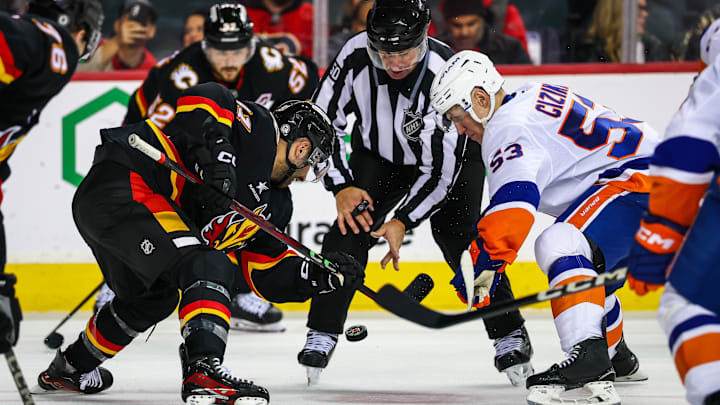 Nov 19, 2024; Calgary, Alberta, CAN; Calgary Flames center Nazem Kadri (91) and New York Islanders center Casey Cizikas (53) face off for the puck during the third period at Scotiabank Saddledome. Mandatory Credit: Sergei Belski-Imagn Images