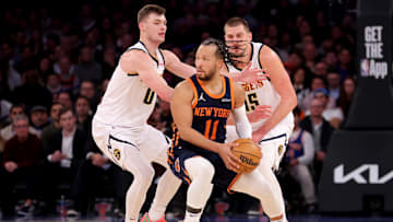 Jan 29, 2025; New York, New York, USA; New York Knicks guard Jalen Brunson (11) controls the ball against Denver Nuggets guard Christian Braun (0) and center Nikola Jokic (15) during the fourth quarter at Madison Square Garden. Mandatory Credit: Brad Penner-Imagn Images