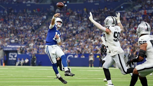 Colts quarterback Daniel Jones (blue and white jersey) throws a pass on the run.