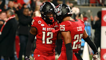 Nov 4, 2023; Raleigh, North Carolina, USA; North Carolina State Wolfpack safety Devan Boykin (12) is greeted by teammate Brandon Cisse (25) after an interception during the second half against the Miami Hurricanes at Carter-Finley Stadium.  Mandatory Credit: Rob Kinnan-Imagn Images