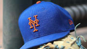 Jul 13, 2022; Atlanta, Georgia, USA; A detailed view of a New York Mets hat and glove in the dugout against the Atlanta Braves in the eighth inning at Truist Park. 