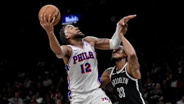 Nov 2, 2025; Brooklyn, New York, USA; Philadelphia 76ers forward Trendon Watford (12) shoots the ball while defended by Brooklyn Nets center Nic Claxton (33) during the first half at Barclays Center. Mandatory Credit: John Jones-Imagn Images
