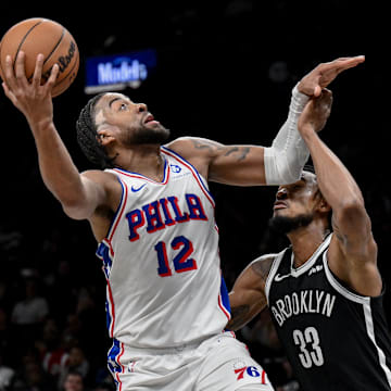 Nov 2, 2025; Brooklyn, New York, USA; Philadelphia 76ers forward Trendon Watford (12) shoots the ball while defended by Brooklyn Nets center Nic Claxton (33) during the first half at Barclays Center. Mandatory Credit: John Jones-Imagn Images