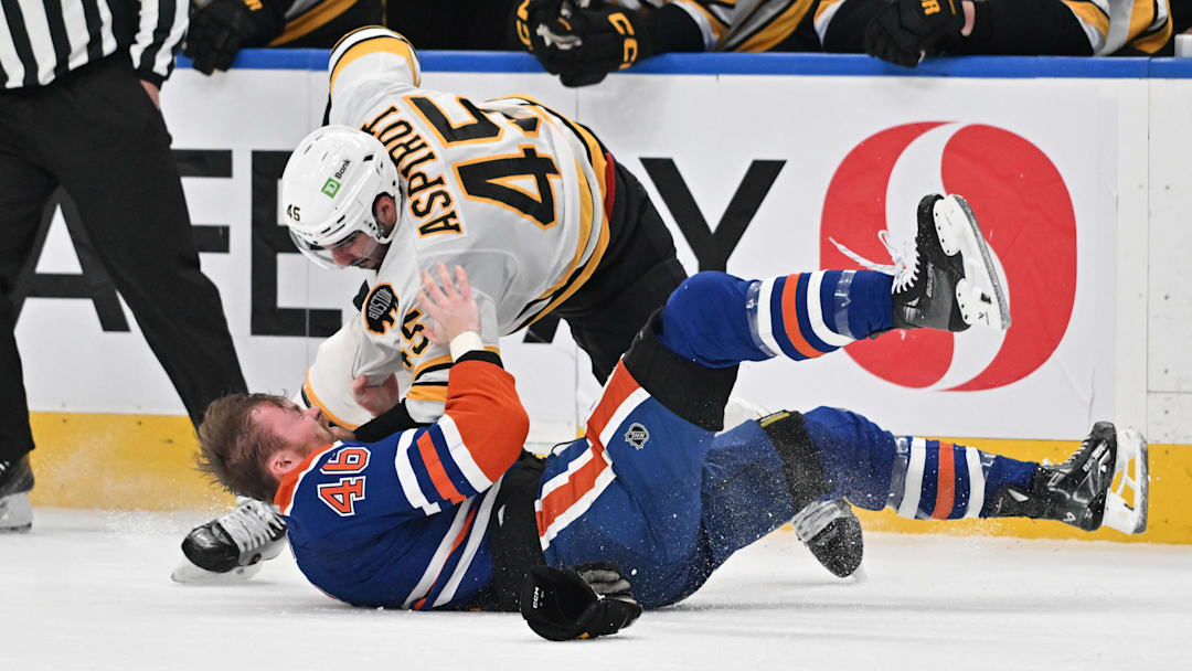 Dec 31, 2025; Edmonton, Alberta, CAN;  Edmonton Oilers left winger Max Jones (46) and Boston Bruins defenseman Jonathan Aspirot (45) fight out on the ice during the third period at Rogers Place. Mandatory Credit: Walter Tychnowicz-Imagn Images