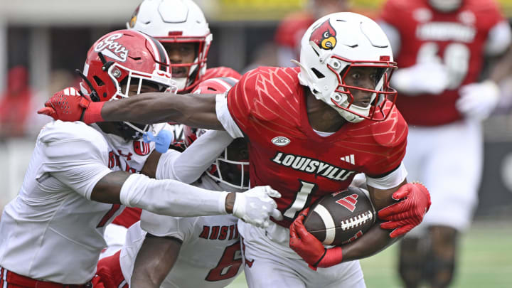 Aug 31, 2024; Louisville, Kentucky, USA;  Louisville Cardinals wide receiver Ja'Corey Brooks (1) tries to escape the tackles of Austin Peay Governors defensive back Jesse Johnson III (1) and Austin Peay Governors linebacker Bo Spearman (6) during the second quarter at L&N Federal Credit Union Stadium.