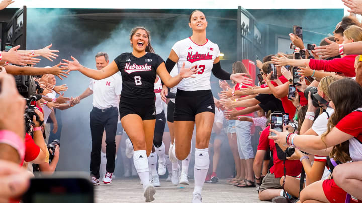 Aug 30, 2023; Lincoln, NE, USA; Nebraska Cornhuskers outside hitter Merritt Beason (13) and libero Lexi Rodriguez (8) run out of the tunnel before the match against the Omaha Mavericks at Memorial Stadium.