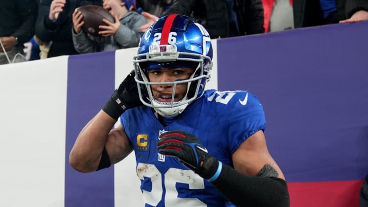 New York Giants running back Saquon Barkley (26) is shown after scoring a touchdown and giving the ball to Harrison Isaacs (background), 6. Harrison traveled with his father Christoper Isaacs (background) to attend his first NFL game, Sunday, January 7, 2024.