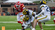 Nov 22, 2025; College Park, Maryland, USA;  Michigan Wolverines defensive back TJ Metcalf (7) and defensive back Zeke Berry (10) tackle Maryland Terrapins wide receiver Octavian Smith Jr. (5) during the first quarter at SECU Stadium. Mandatory Credit: Tommy Gilligan-Imagn Images