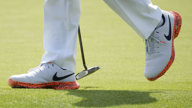 Rory McIlroy wears white and orange Nike golf shoes.