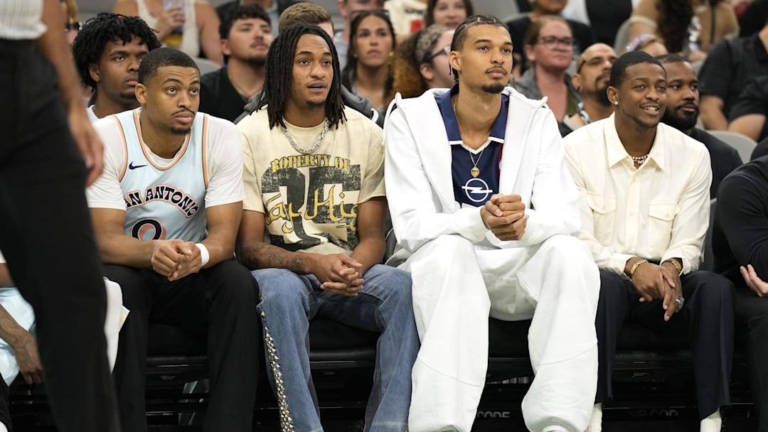 Apr 13, 2025; San Antonio, Texas, USA; San Antonio Spurs (from left to right) forward Keldon Johnson (0), guard Devin Vassell (24), center Victor Wembanyama (1) and guard De'Aron Fox (4) watch the first half of a game against the Toronto Raptors at Frost Bank Center. Mandatory Credit: Scott Wachter-Imagn Images