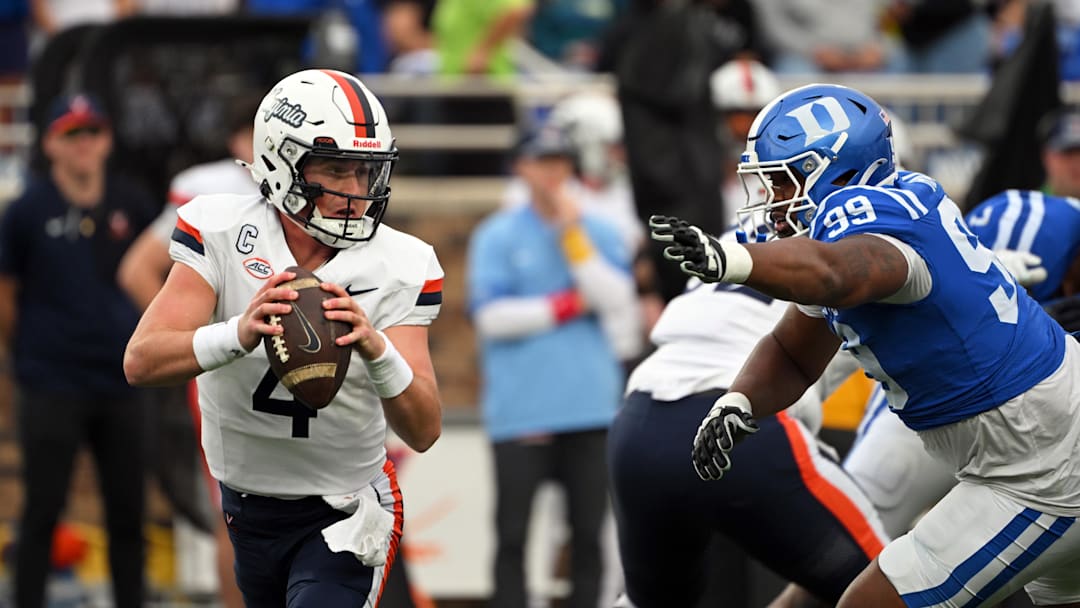 Nov 15, 2025; Durham, North Carolina, USA;  Virginia Cavaliers quarter back Chandler Morris (4) looks for an opening against Duke Blue Devils defensive tackle Aaron Hall (99) during the first quarter at Wallace Wade Stadium. Mandatory Credit: Zachary Taft-Imagn Images