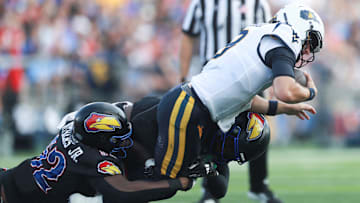 Kansas Jayhawks defensive tackle D.J. Withers (52) brings down West Virginia Mountaineers quarterback Nicco Marchiol (8) during the first half of the game against West Virginia Mountaineers at David Booth Kansas Memorial Stadium on Sept. 20, 2025.