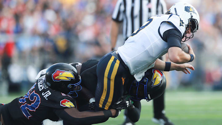Kansas Jayhawks defensive tackle D.J. Withers (52) brings down West Virginia Mountaineers quarterback Nicco Marchiol (8) during the first half of the game against West Virginia Mountaineers at David Booth Kansas Memorial Stadium on Sept. 20, 2025.