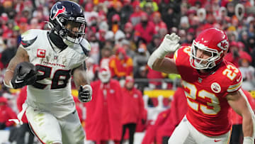 Jan 18, 2025; Kansas City, Missouri, USA; Houston Texans running back Joe Mixon (28) runs the ball as Kansas City Chiefs linebacker Drue Tranquill (23) defends during the second half of a 2025 AFC divisional round game at GEHA Field at Arrowhead Stadium.