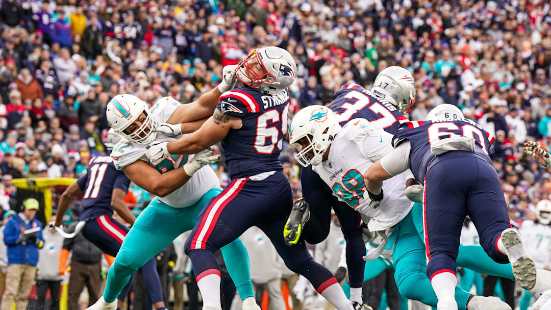 Jan 1, 2023; Foxborough, Massachusetts, USA; New England Patriots guard Cole Strange (69) hold off Miami Dolphins defense in the first half at Gillette Stadium. Mandatory Credit: David Butler II-Imagn Images