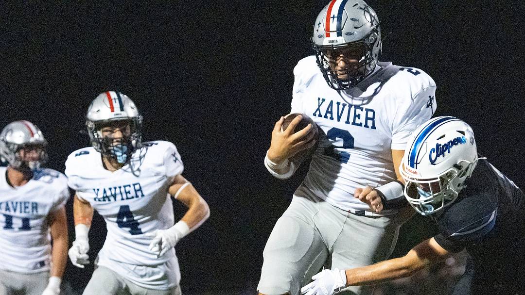 Xavier’s Cash Parks (2) breaks a tackle by a Clear Creek Amana defender before rushing into the endzone during a high school football game Sept. 11, 2026 in Tiffin, Iowa.