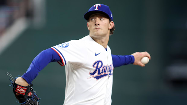 Texas Rangers relief pitcher Jacob Latz (67) throws a pitch in a white uniform and blue hat
