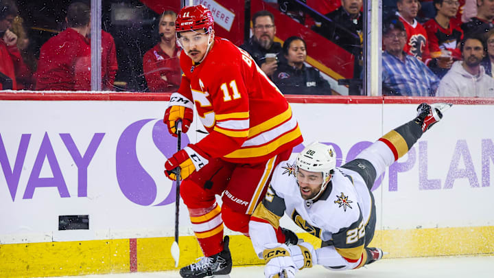 Nov 27, 2023; Calgary, Alberta, CAN; Calgary Flames center Mikael Backlund (11) and Vegas Golden Knights right wing Michael Amadio (22) battle for the puck during the third period at Scotiabank Saddledome. Mandatory Credit: Sergei Belski-Imagn Images