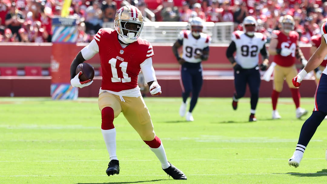 Sep 29, 2024; Santa Clara, California, USA; San Francisco 49ers wide receiver Brandon Aiyuk (11) runs with the ball past New England Patriots linebacker Jahlani Tavai (48) during the first quarter at Levi's Stadium. Mandatory Credit: Sergio Estrada-Imagn Images