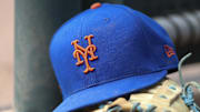 Jul 13, 2022; Atlanta, Georgia, USA; A detailed view of a New York Mets hat and glove in the dugout against the Atlanta Braves in the eighth inning at Truist Park.