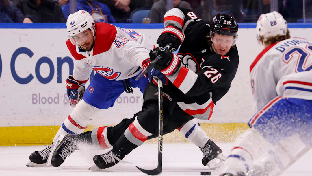 Mar 1, 2025; Buffalo, New York, USA;  Buffalo Sabres defenseman Rasmus Dahlin (26) gets knocked down by Montreal Canadiens defenseman Alexandre Carrier (45) as he goes after the puck during the first period at KeyBank Center. Mandatory Credit: Timothy T. Ludwig-Imagn Images