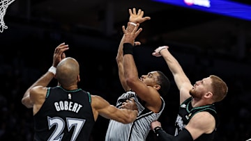 Nov 30, 2025; Minneapolis, Minnesota, USA; San Antonio Spurs forward Keldon Johnson (3) shoots as Minnesota Timberwolves center Rudy Gobert (27) and guard Donte DiVincenzo (0) defend during the first half at Target Center. Mandatory Credit: Matt Krohn-Imagn Images