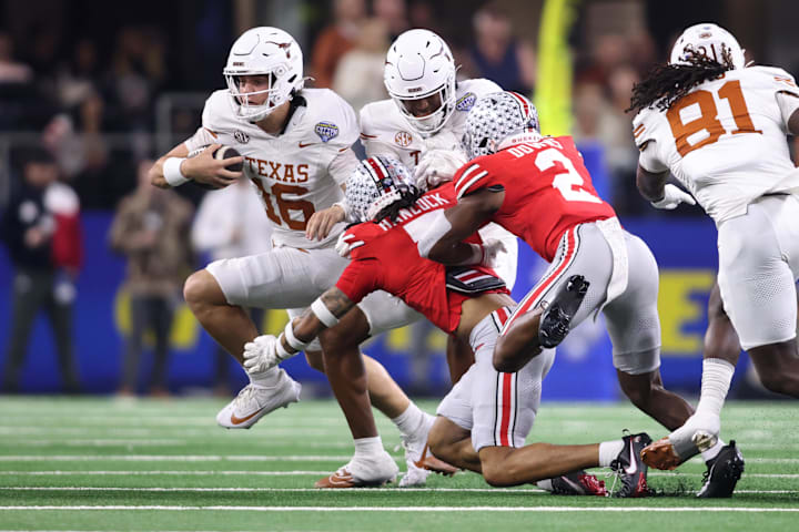 Texas Longhorns quarterback Arch Manning runs against Ohio State Buckeyes DBs Jordan Hancock and Caleb Downs during the CF